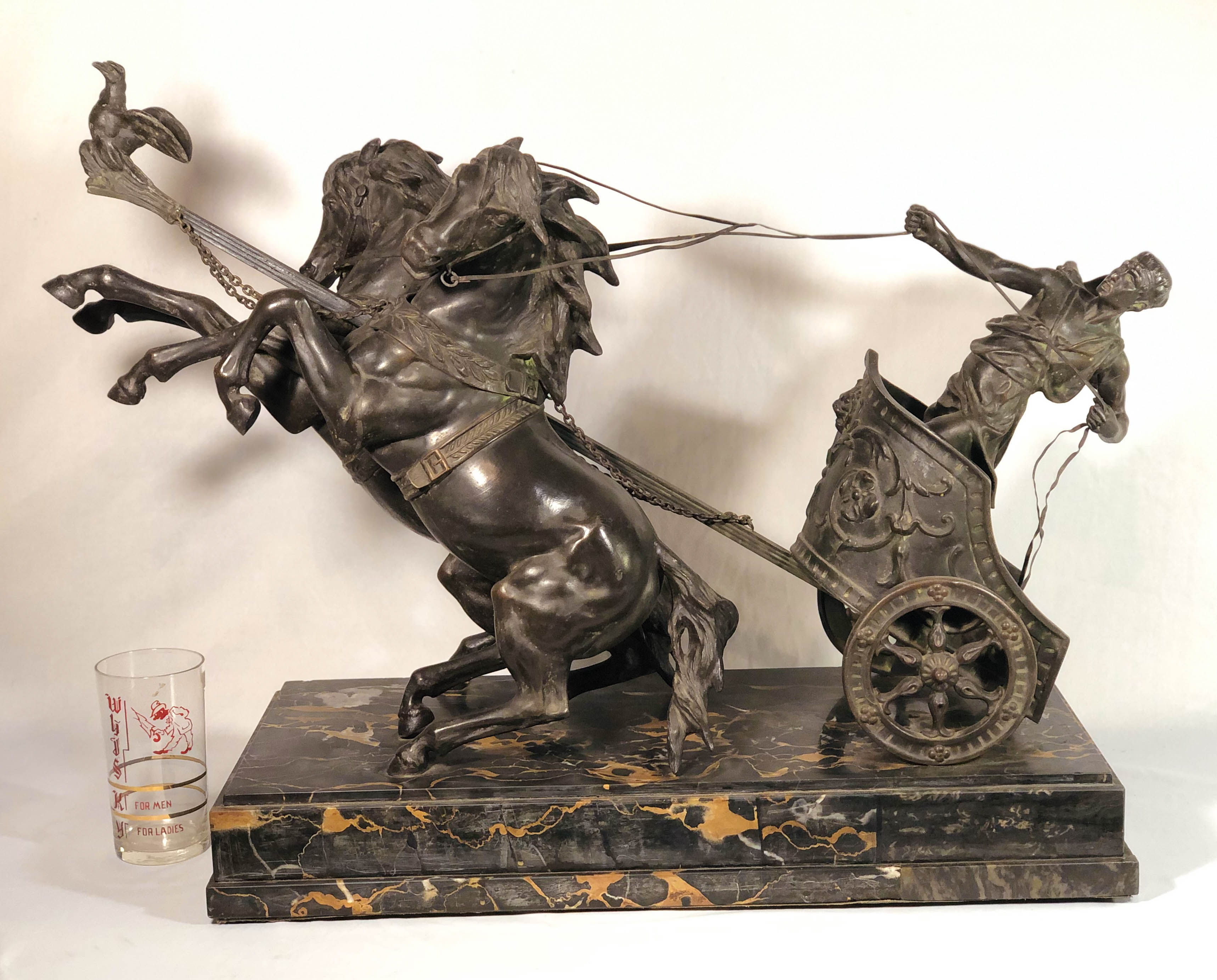 Domenech et Pfeffer (SEC. XIX). Antiga e rara biga romana confeccionada em bronze, intitulada Char de la Victoire (Carruagem da Vitória). Ricamente detalhada, é composta por homem em carruagem e dois cavalos em bronze presos a base em mármore escuro que possui assinatura Domenech et Pfeffer. Está em ótimas condições. Aconselhamos retirada pessoal ou por transportadora especializada. Medidas: 74cm de maior comprimento, 26cm de largura e 53cm de maior altura.