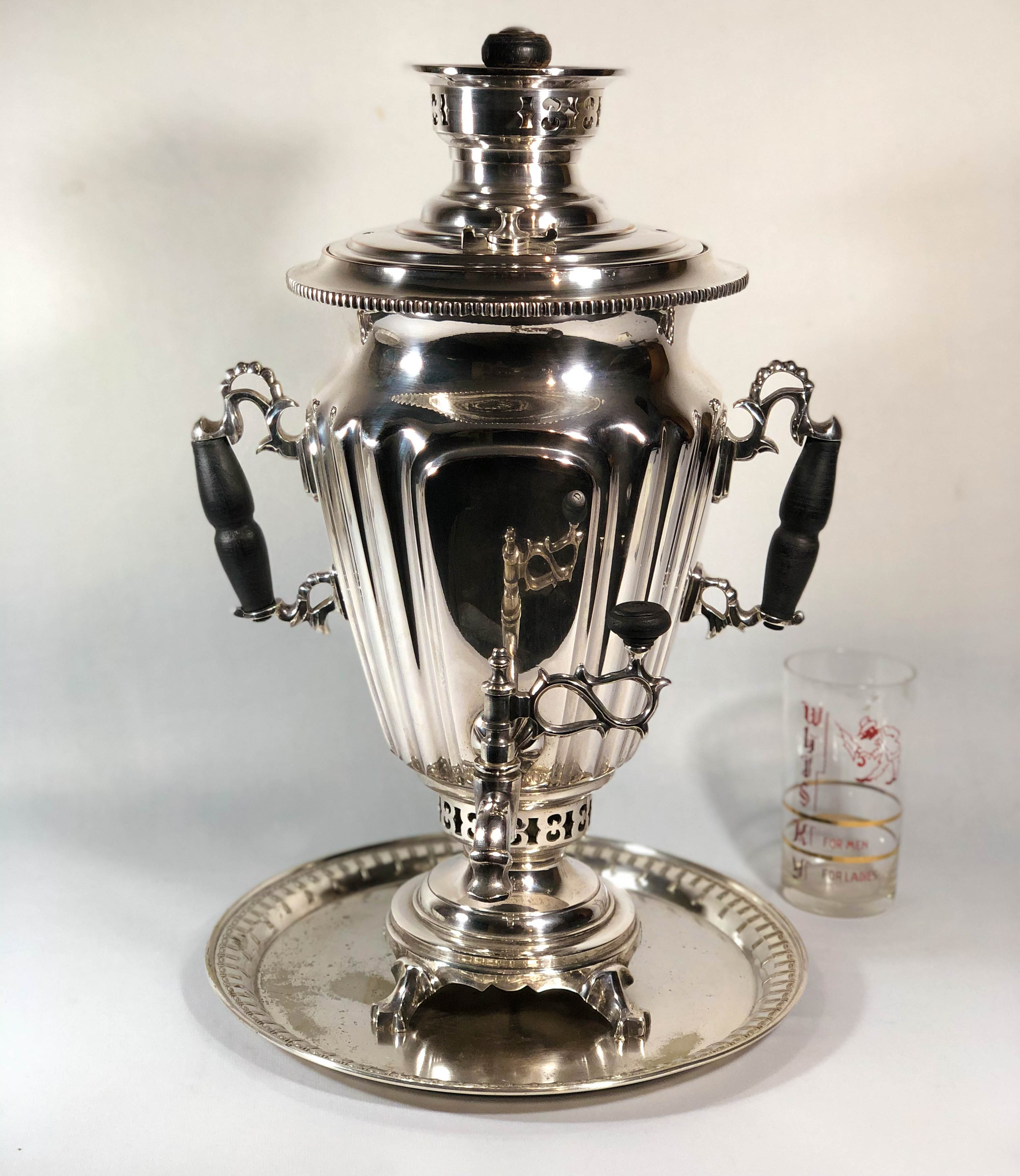 Samovar Russo conforme contraste na foto. Belíssima peça em metal espessurado a prata, contendo pés de garra, pegas laterais com belíssimo trabalho e terminação em madeira. Torneira com terminação em madeira, trabalho de cinzelaria na parte superior adornando a tampa. Medidas: 48cm de altura e 32cm de largura de pega a pega.